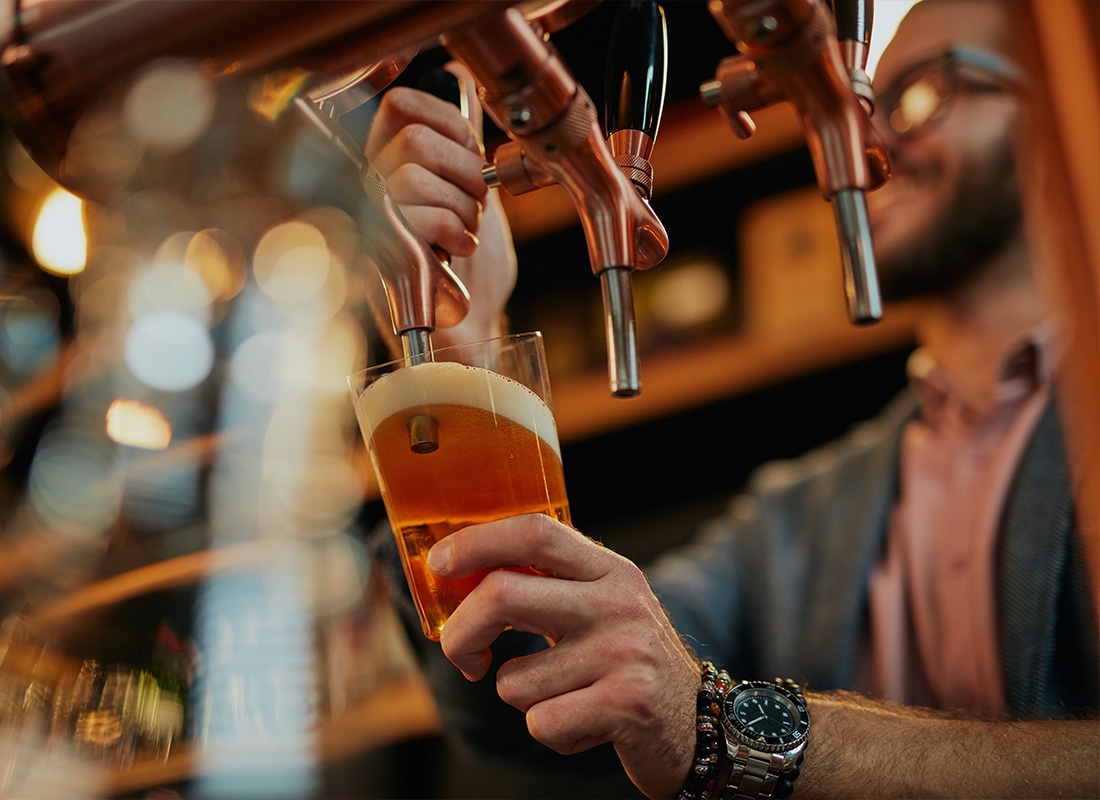 Insurance by Industry - Tattooed Barman Pouring Beer While Standing in Pub