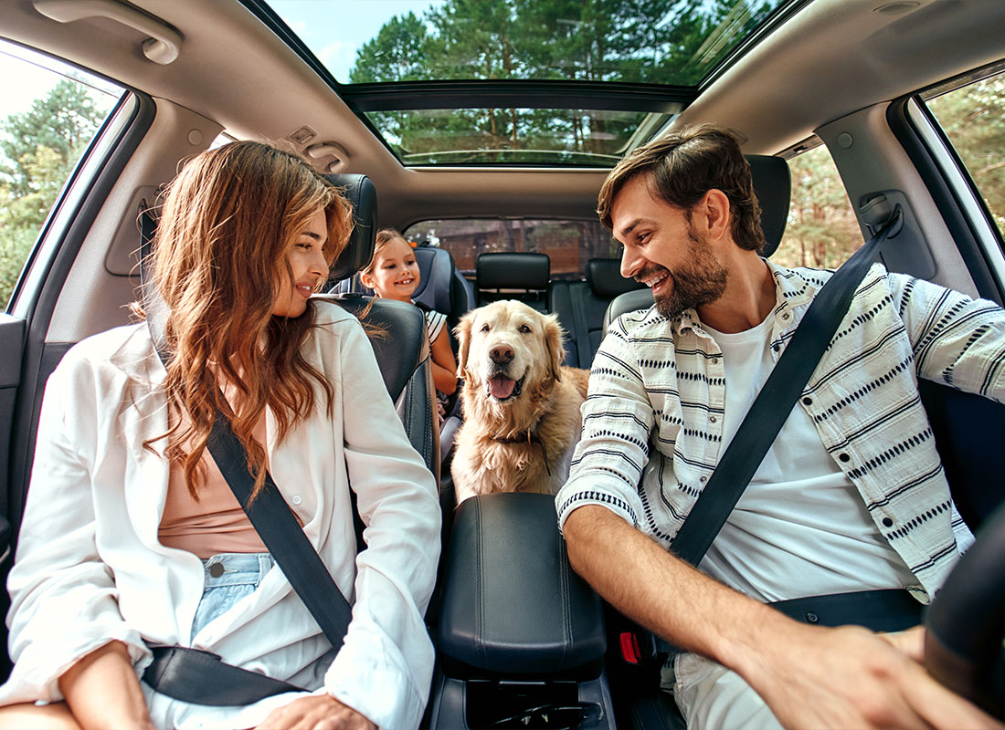 Personal Insurance - Mother and Father Sitting in the Passenger Seat and Driver Seat With Daughter and Family Dog Sitting in the Back Seat
